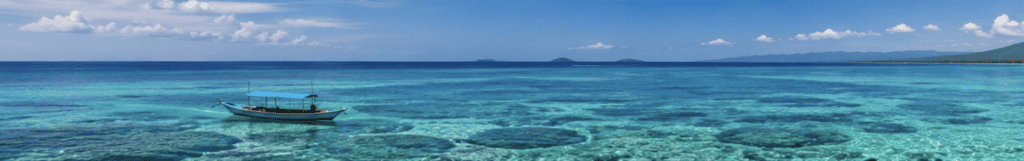 Aerial view of a boat anchored over a coral reef in shallow turquoise water