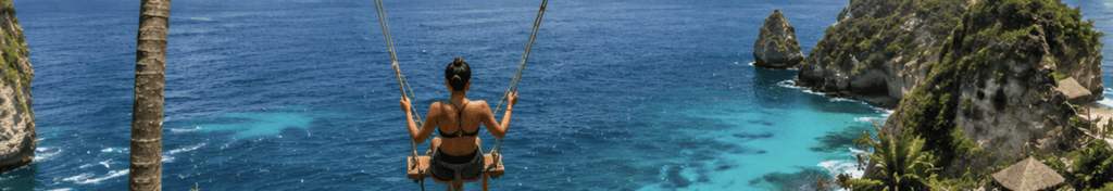 Woman on a cliffside rope swing overlooking the ocean and a rocky outcrop near Canggu